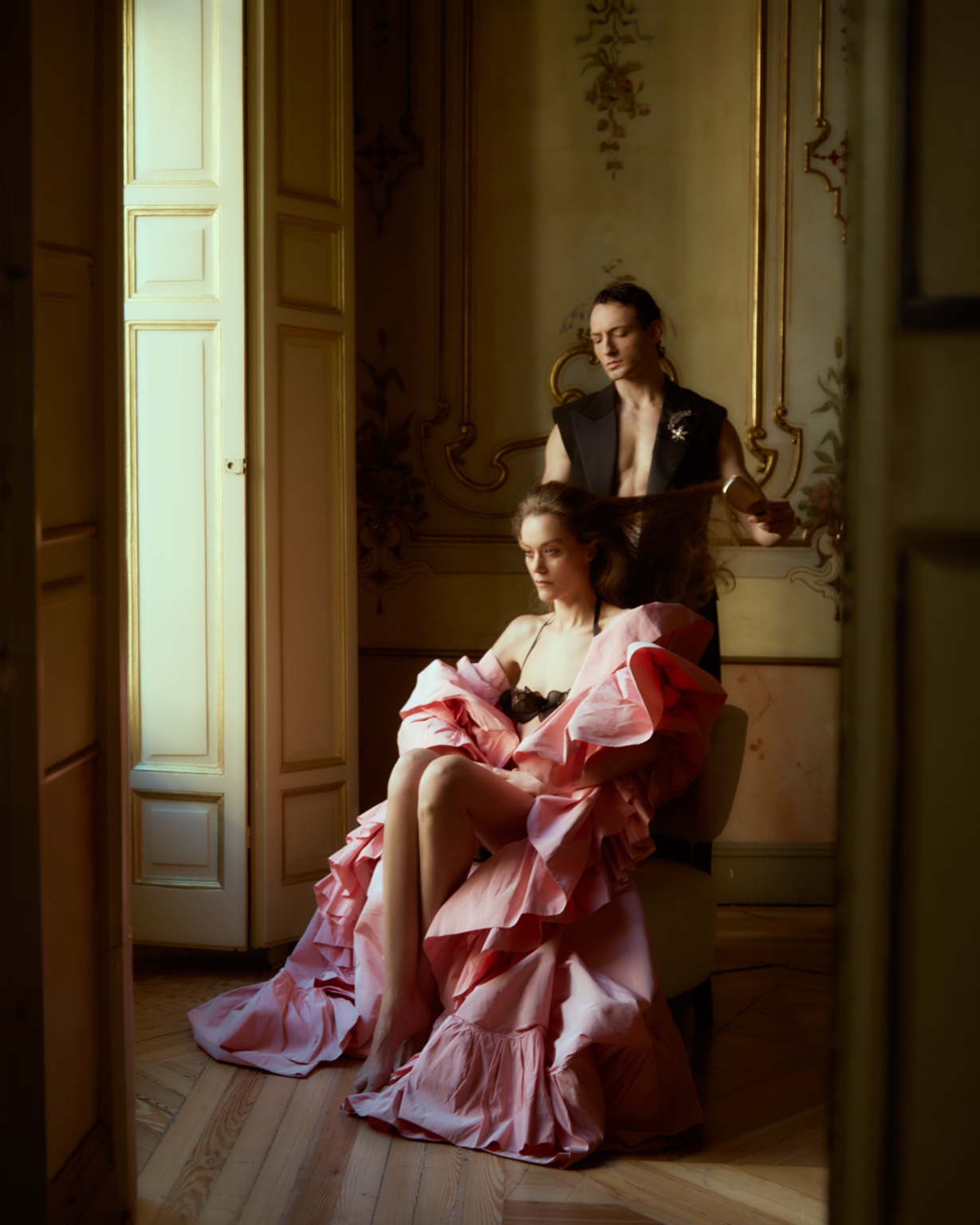 The butler styling a woman in a pink dress